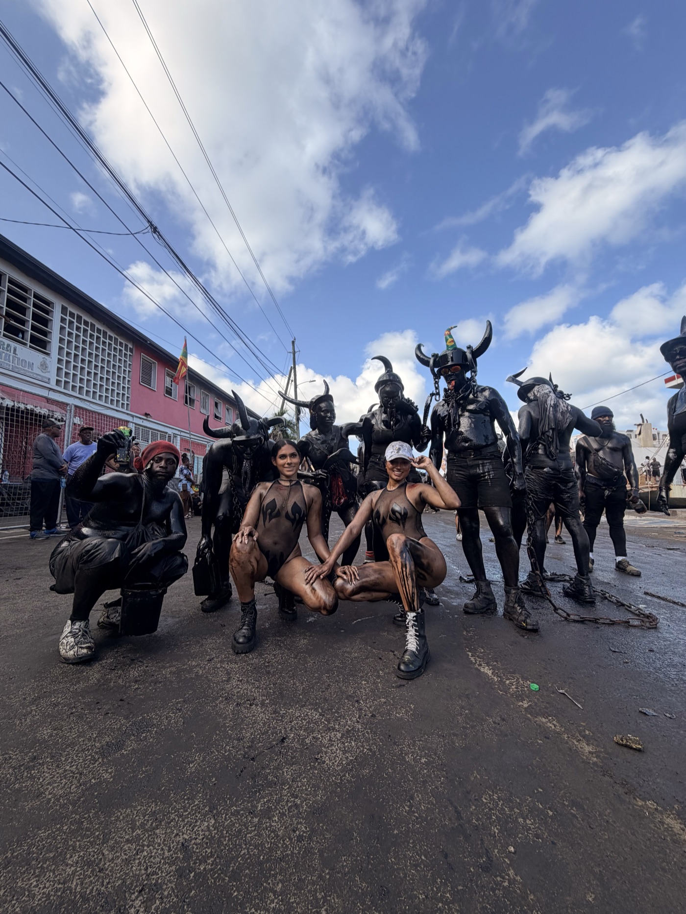 Dania Duntin and Emma Aqui covered in oil with local Jab Jab masqueraders in St George's, Grenada